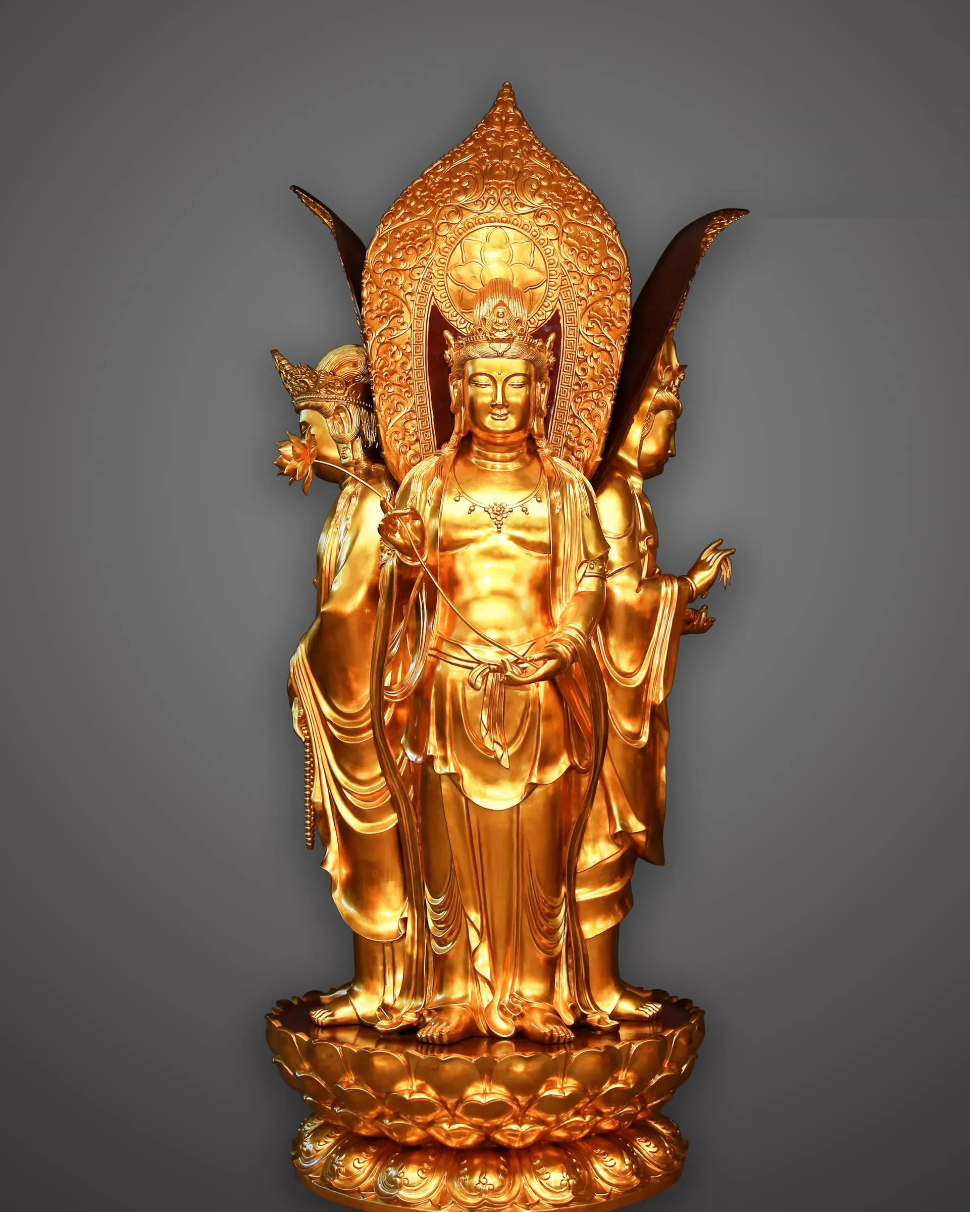 Gilded standing Guanyin with four faces before a flame-shaped halo.