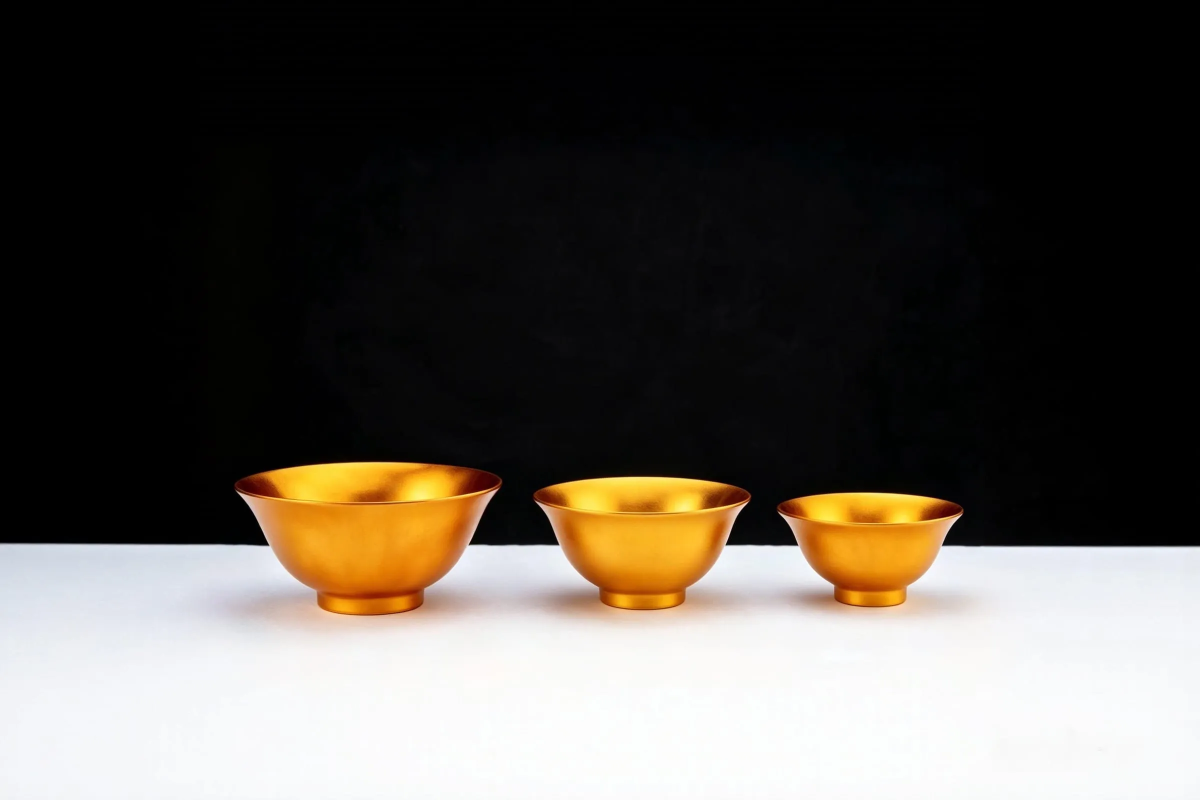 Three gold bowls of graduated size on a white surface.