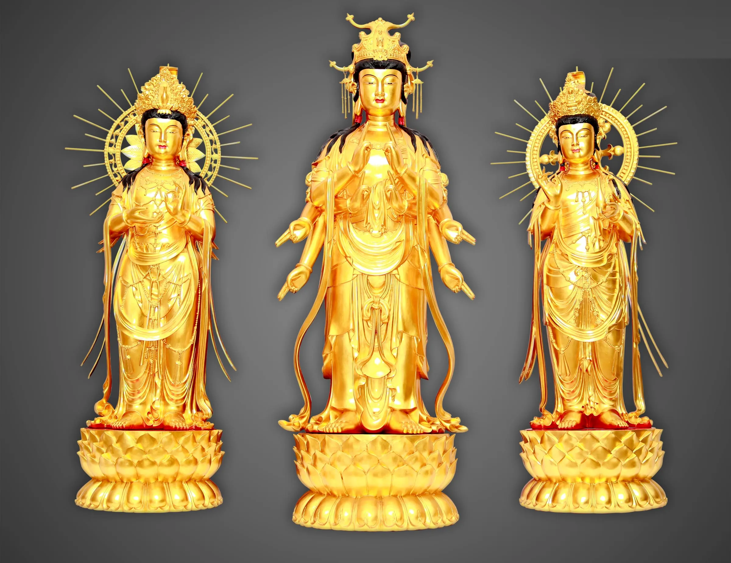 Three gilded standing figures on lotus bases, the outer two with radiating halos.