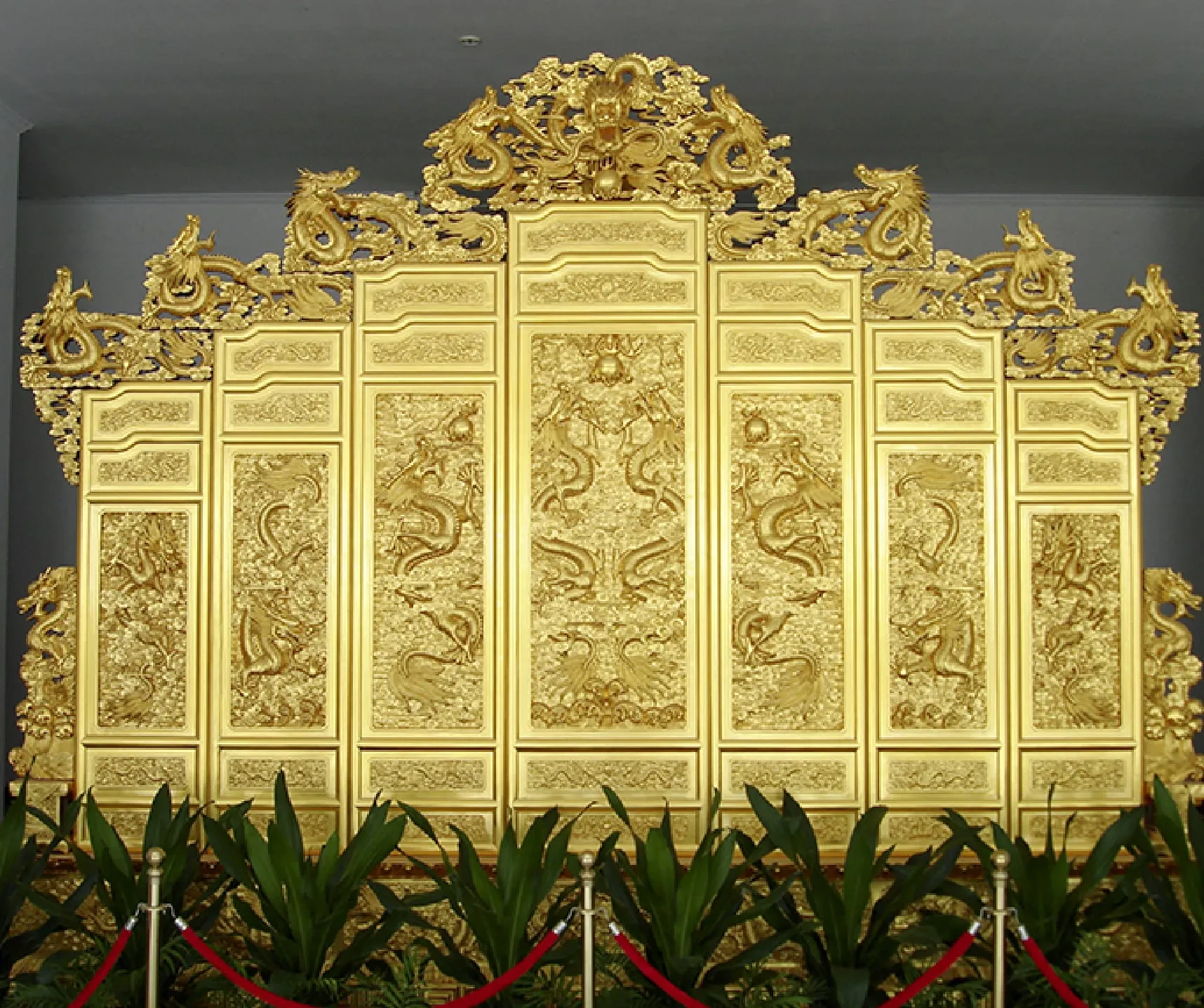 A multi-panel gold screen carved with dragons, crowned by an openwork crest.