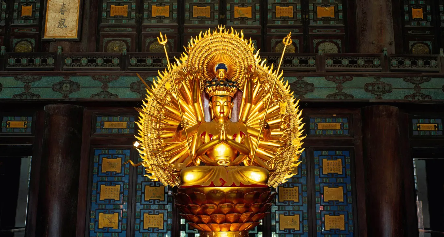 A gilded thousand-armed Guanyin seated on a lotus pedestal inside the Palace Museum, Beijing.